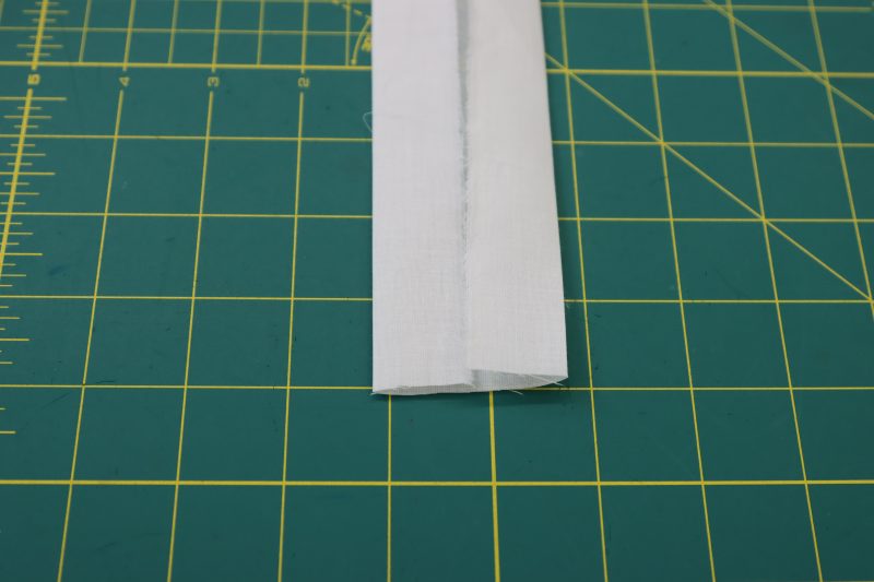 How To Fold Waistband Edges Toward Center And Press - Cotton Voile - Mood Fabrics - Selenite V Waist Ballgown Free Sewing Pattern Tutorial - MDF515 - Mood Fabrics Sewciety Blog - Fold the long raw edges towards the center of the strip.