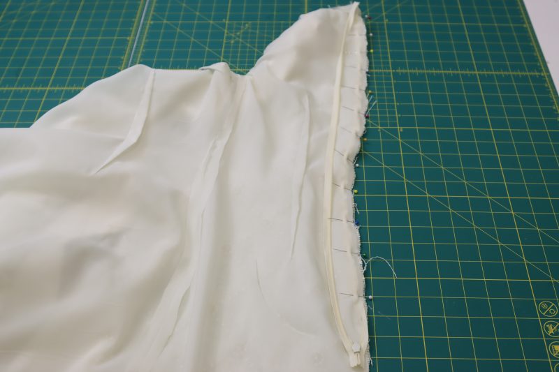 How To Pin Zipper Right Sides Together Between Main Fabric And Lining - Invisible Zipper - Mood Fabrics - Deauville Cocktail Dress Free Sewing Pattern Tutorial - MDF517 - Mood Fabrics Sewciety Blog - Pin the zipper right sides together between the main fabric and the lining.