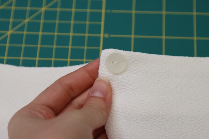 How To Sew Button At The Top Of The Center Back Opening Of The Blouse - Ivory Two Hole Button - Mood Fabrics - Merano Balloon Sleeve Blouse Free Sewing Pattern Tutorial - MDF522 - Mood Fabrics Sewciety Blog - Hand sew a button at the top of the center back opening of the blouse.
