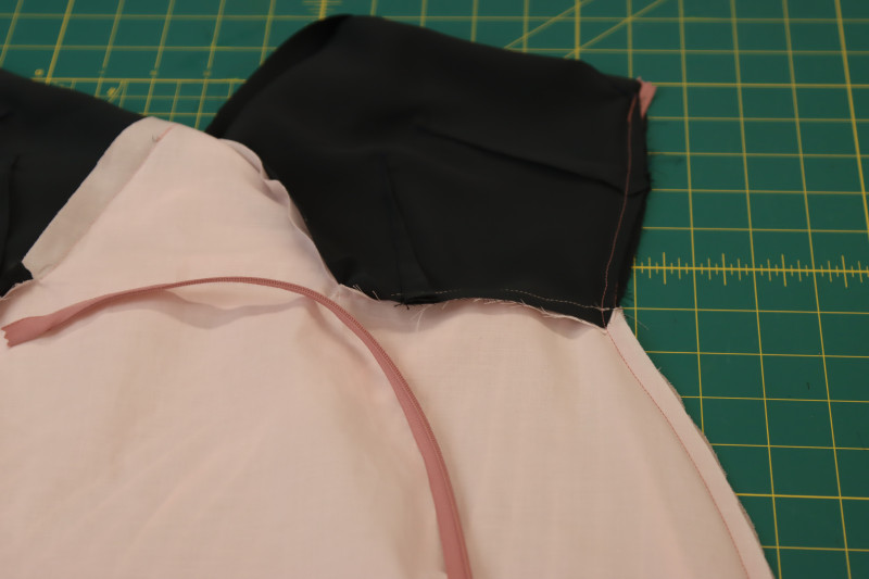 How To Sandwich First Side Of Zipper Tape Between Lining And Main Fabric - Invisible Zipper - Mood Fabrics - Pyrite Pleated Dress Free Sewing Pattern Tutorial - MDF527 - Mood Fabrics Sewciety Blog - Sandwich the first side of the zipper tape between the lining and the main fabric.