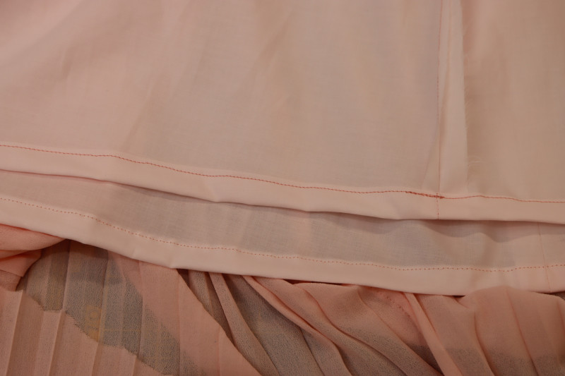 How To Sew Half Inch Double Rolled Hem On Bottom Of Lining Skirt - Japanese Pima Cotton Lawn - Mood Fabrics - Pyrite Pleated Dress Free Sewing Pattern Tutorial - MDF527 - Mood Fabrics Sewciety Blog - Sew a ½ inch double rolled hem on the bottom of the lining skirt.