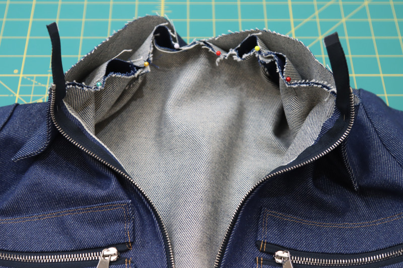 How To Pin Collar Attached To Neckline First Layer - Cotton Denim Twill - Mood Fabrics - Merit Jumpsuit Free Sewing Pattern Tutorial - MDF525 - Mood Fabrics Sewciety Blog - Pin one of the raw edges of the collar to the neckline.