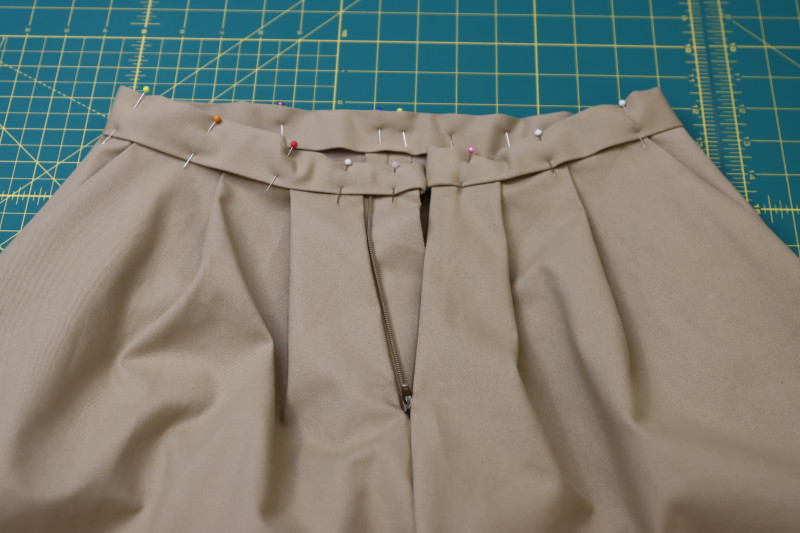 How To Pin Waistband To Waistline Of Pants - Stretch Khaki Twill - Mood Fabrics - Lucca Tailored Barrel Leg Pants Free Sewing Pattern Tutorial - MDF524 - Mood Fabrics Sewciety Blog - Pin the waistband to the waistline of the pants.