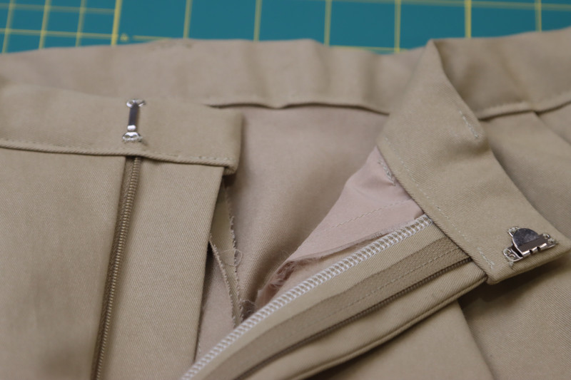 How To Sew Hook And Eye Closure To Inside Of Waistband Where Two Ends Overlap - Hook And Eye Closures - Mood Fabrics - Lucca Tailored Barrel Leg Pants Free Sewing Pattern Tutorial - MDF524 - Mood Fabrics Sewciety Blog - Hand sew the hook and eye closure to the inside of the waistband where the two ends overlap.