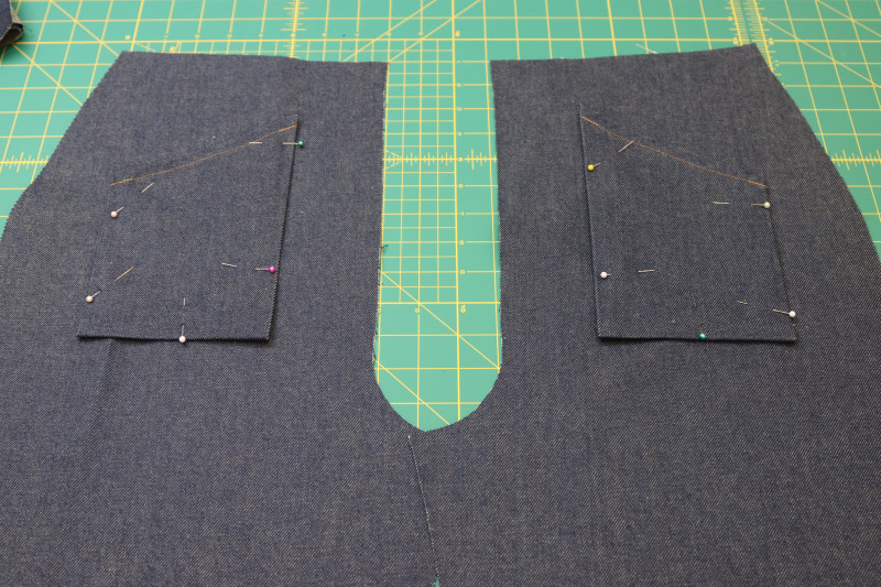 How To Pin Front Pockets Pinned To Pants - Cotton Denim Twill - Mood Fabrics - Merit Jumpsuit Free Sewing Pattern Tutorial - MDF525 - Mood Fabrics Sewciety Blog - Pin the front pockets to the fronts of the pants at the chalk lines.
