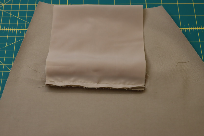 How To Pin Sew Pocket Lining To Bottom Welt Seam Allowance - Stretch Polester Twill Lining - Mood Fabrics - Lucca Tailored Barrel Leg Pants Free Sewing Pattern Tutorial - MDF524 - Mood Fabrics Sewciety Blog - Pin and sew the pocket lining to the bottom welt seam allowance.