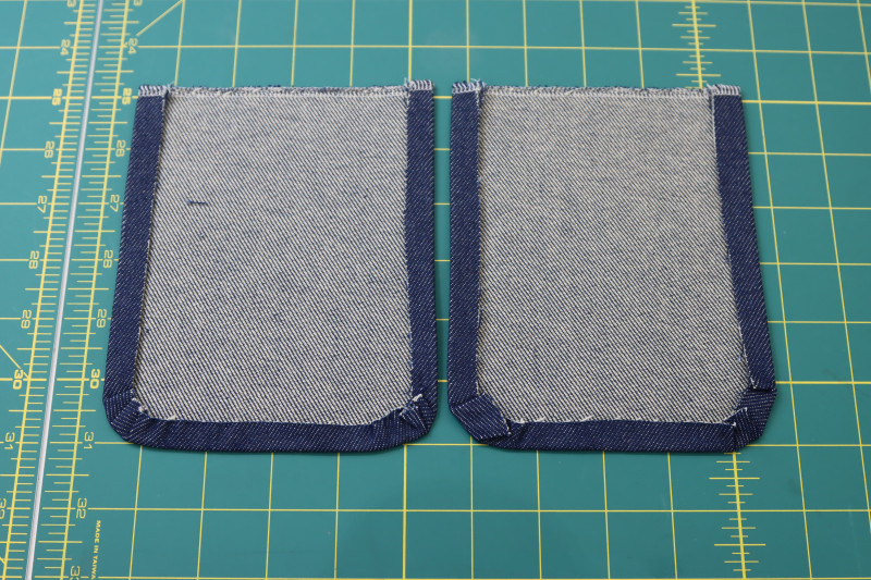 How To Fold Breast Pocket Sides And Bottoms Folded And Pressed - Cotton Denim Twill - Mood Fabrics - Merit Jumpsuit Free Sewing Pattern Tutorial - MDF525 - Mood Fabrics Sewciety Blog - Fold and press the sides and bottoms of the breast pockets.