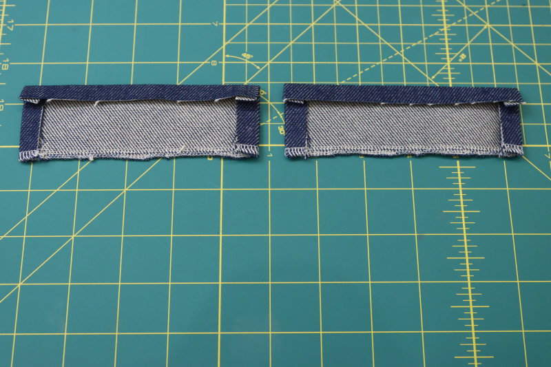 How To Fold Upper Front Pocket Pieces Tops And Sides Folded And Pressed - Cotton Denim Twill - Mood Fabrics - Merit Jumpsuit Free Sewing Pattern Tutorial - MDF525 - Mood Fabrics Sewciety Blog - Fold and press the tops and sides of the upper front pocket pieces.