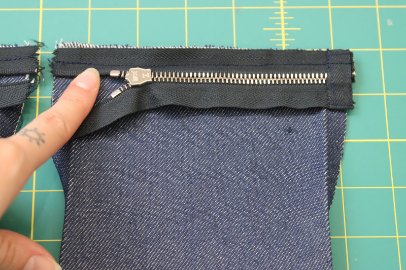 How To Pin Sew Zipper Attached To Breast Pocket Top Edge - 9 Inch Zipper - Mood Fabrics - Merit Jumpsuit Free Sewing Pattern Tutorial - MDF525 - Mood Fabrics Sewciety Blog - Pin and sew the zipper right sides together with the top edge of the breast pocket.