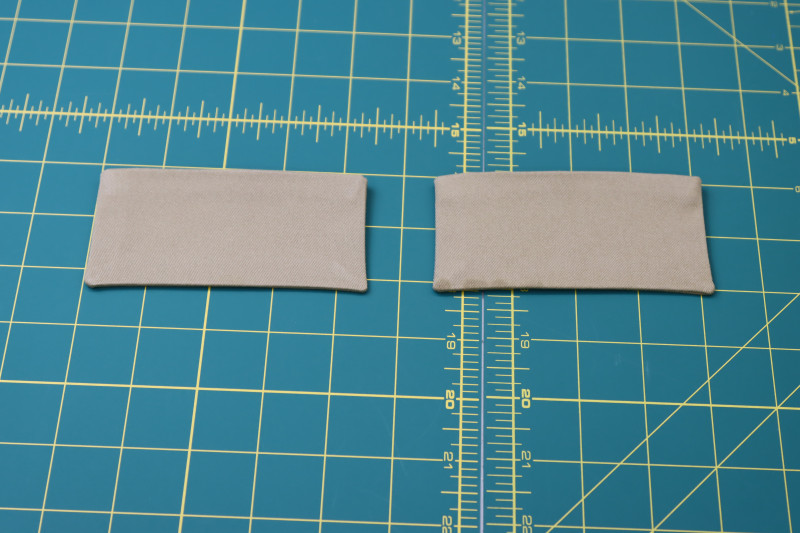 How To Press Folded Edges Of Pocket Flaps Into Inside Of Flaps - Stretch Khaki Twill - Mood Fabrics - Lucca Tailored Barrel Leg Pants Free Sewing Pattern Tutorial - MDF524 - Mood Fabrics Sewciety Blog - Press the folded edges of the pocket flaps into the inside of the flaps.