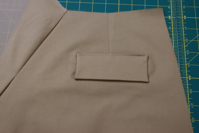 How To Sew Pocket Flaps To Upper Seam Allowance Of Welt Pocket - Stretch Khaki Twill - Mood Fabrics - Lucca Tailored Barrel Leg Pants Free Sewing Pattern Tutorial - MDF524 - Mood Fabrics Sewciety Blog - Sew the pocket flaps to the upper seam allowance of the welt pocket.