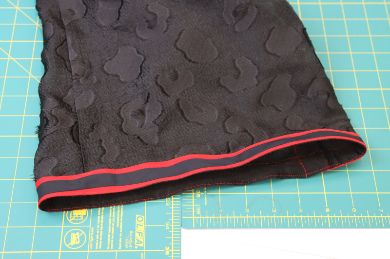 How To Flip Trim Outside Pants Hem - Red Quilting Cotton - Mood Fabrics - Matrix Shawl Collar Ensemble Free Sewing Pattern Tutorial - MDF543 - Mood Fabrics Sewciety Blog - Flip the trim to the outside of the pants hem.