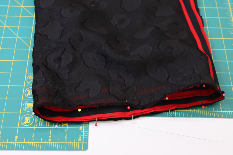 How To Pin Sew Trim Wrong Side Pants Hem - Red Quilting Cotton - Mood Fabrics - Matrix Shawl Collar Ensemble Free Sewing Pattern Tutorial - MDF543 - Mood Fabrics Sewciety Blog - Pin and sew the trim to the wrong side of the pants hem.
