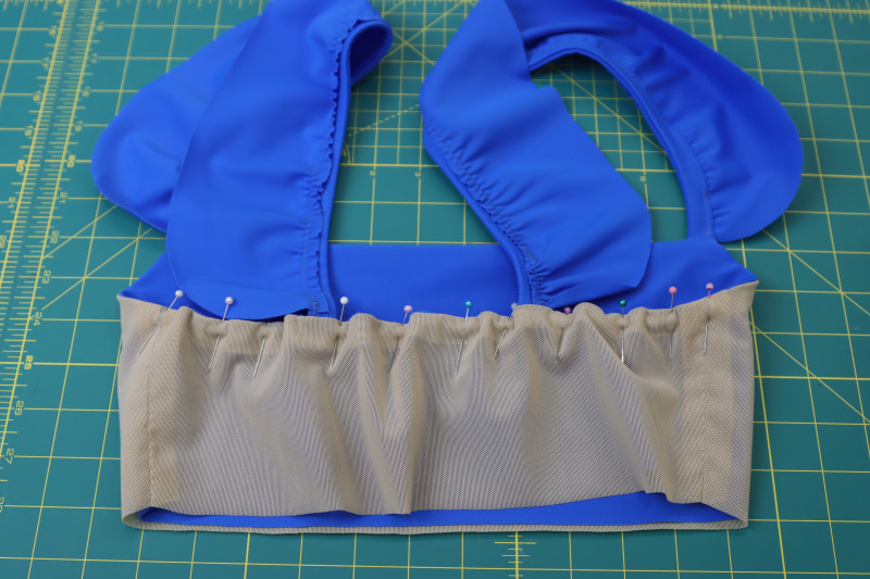 How To Pin Elastic Between Two Side Seams At Back Neckline Of Bikini Top - Dritz Cotton Swimwear Elastic - Mood Fabrics - Azure Tankini Skirt Set Free Sewing Pattern Tutorial - MDF533 - Mood Fabrics Sewciety Blog - Pin the elastic between the two side seams at the back neckline of the bikini top.
