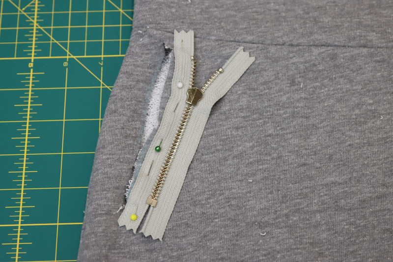 How To Pin Sew Zipper Right Sides Together With Inner Edge Of Pocket Slit - 4.5 Inch Metal Teeth Zipper - Mood Fabrics - Reef Sleeveless Cover Up Free Sewing Pattern Tutorial - MDF535 - Mood Fabrics Sewciety Blog - Pin the zipper right sides together with the inner edge of the pocket slit.