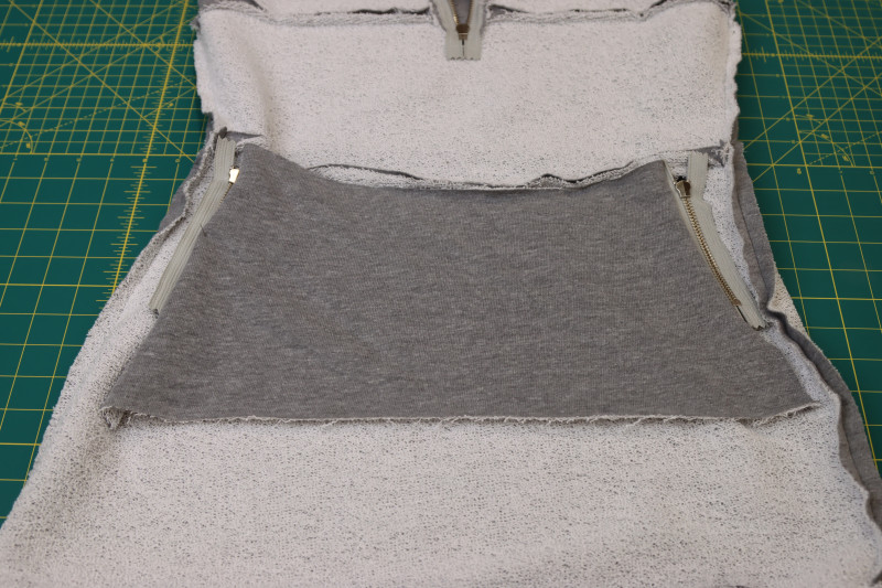 How To Flip Pocket Bag Into Wrong Side Of Skirt And Pin To Other Zippered Pocket - Heather Gray French Terry - Mood Fabrics - Reef Sleeveless Cover Up Free Sewing Pattern Tutorial - MDF535 - Mood Fabrics Sewciety Blog - Flip the pocket bag into the wrong side of the skirt and pin and sew it right sides together to the other zippered pocket.