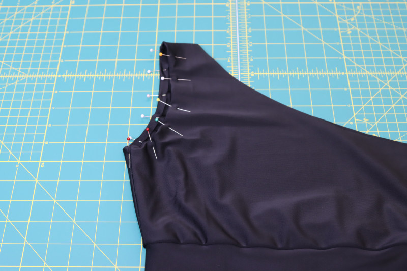How To Fold Raw Edges Of Armscye Toward Inside Of Bikini Top - Recycled Swimwear Tricot - Mood Fabrics - Antikythera One Shoulder Bikini Free Sewing Pattern Tutorial - MDF531 - Mood Fabrics Sewciety Blog - Fold the raw edges of the armscye toward the inside of the bikini and topstitch over the hem.