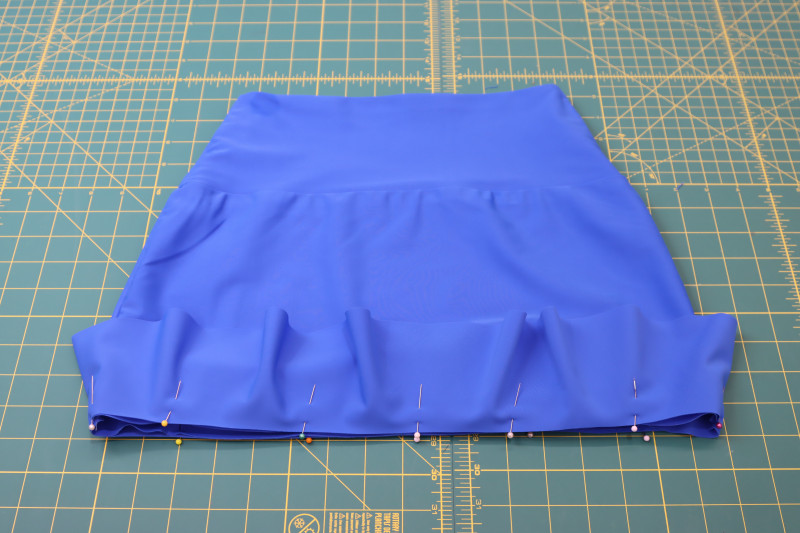 How To Pin Skirt Ruffle To Hem Of Skirt - Recycled Swimwear Tricot - Mood Fabrics - Azure Tankini Skirt Set Free Sewing Pattern Tutorial - MDF533 - Mood Fabrics Sewciety Blog - Pin the skirt ruffle to the hem of the skirt.