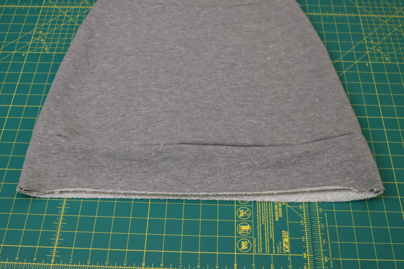 How To Flip Hem Band Down And Seam Open And Flat - Heather Gray French Terry - Mood Fabrics - Reef Sleeveless Cover Up Free Sewing Pattern Tutorial - MDF535 - Mood Fabrics Sewciety Blog - Flip the hem band down and press the seam open and flat.