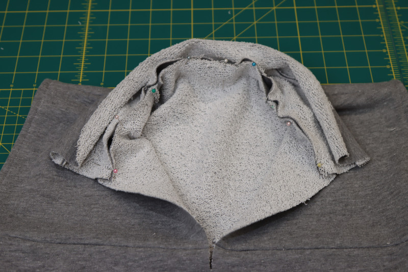 How To Pin Raw Edges Of Collar To Neckline Of Cover Up - Heather Gray French Terry - Mood Fabrics - Reef Sleeveless Cover Up Free Sewing Pattern Tutorial - MDF535 - Mood Fabrics Sewciety Blog - Pin one of the raw edges of the collar to the neckline of the cover up.