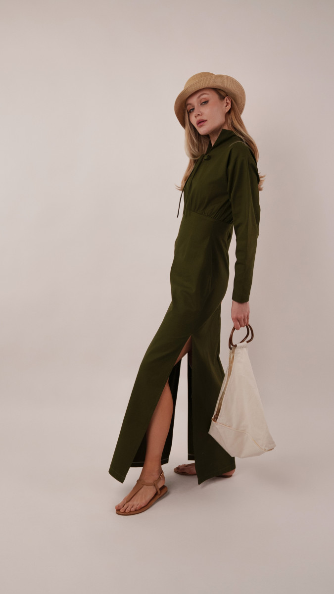 Model wearing the olive green Boca Resort Dress and carrying an ivory Spirea Tote Bag while overlooking a coastal view for a vacation capsule farewell look.