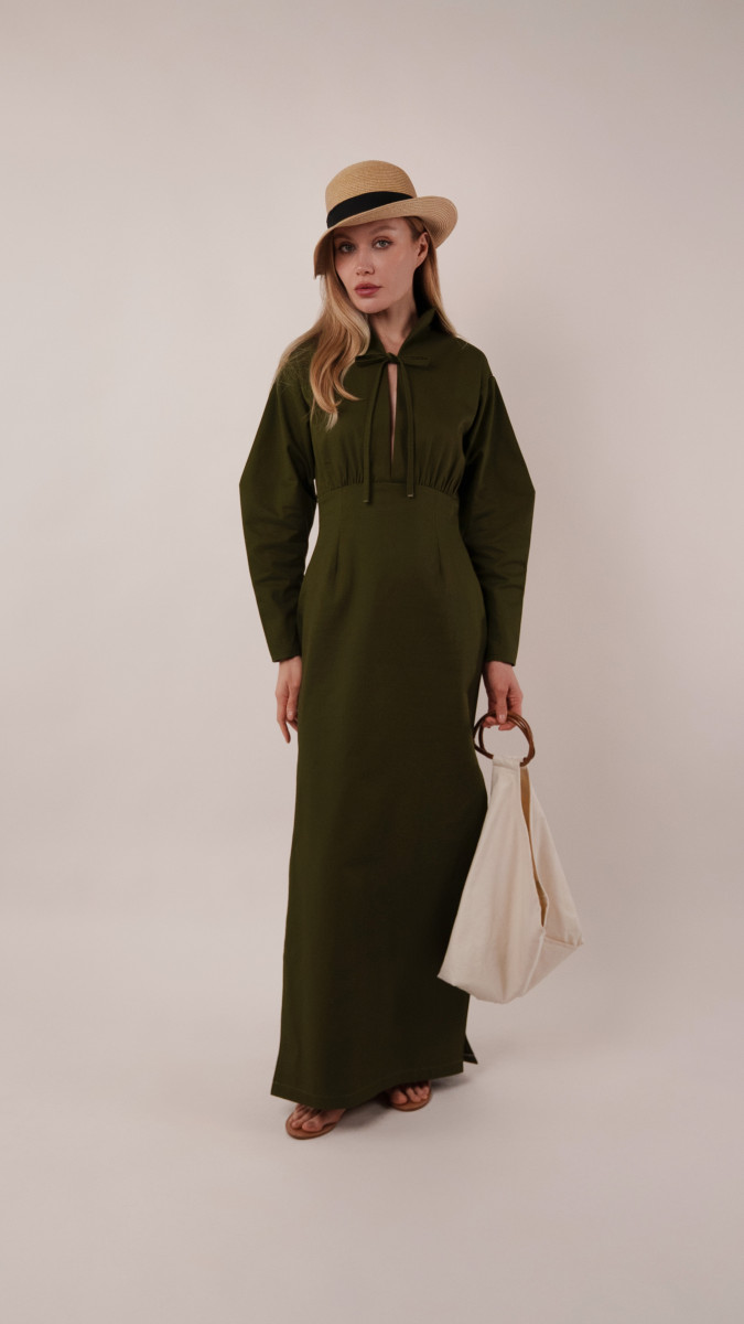 Model wearing the olive green Boca Resort Dress and carrying an ivory Spirea Tote Bag while overlooking a coastal view for a vacation capsule farewell look.