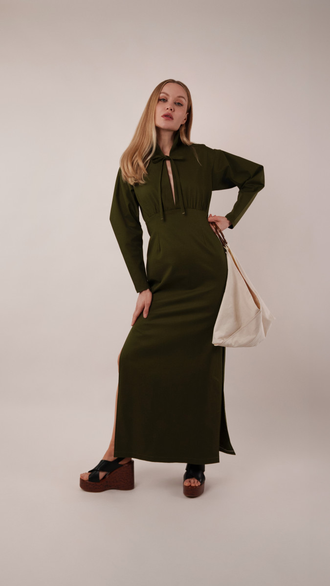 Model wearing a floor-length olive green Boca Resort Dress and platform wedges for a sophisticated sightseeing outfit from our vacation capsule.