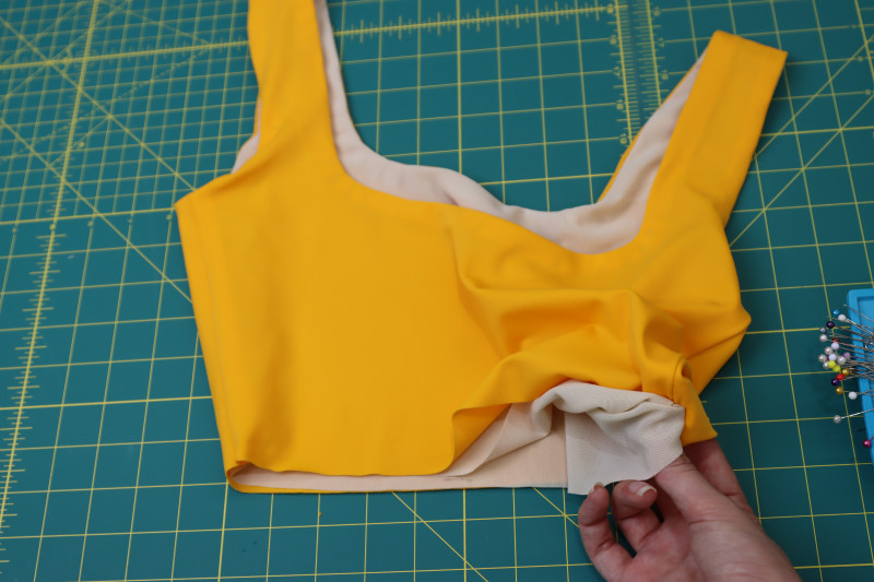 How To Pinch Top Waistline Side Seam Lining Main Fabric - UV Protective Swimwear Tricot - Mood Fabrics - Amber Two Piece Cheeky Swimsuit Free Sewing Pattern Tutorial - MDF540 - Mood Fabrics Sewciety Blog - Pinch the lining fabric and main fabric right sides together at the waistline side seam of the top.