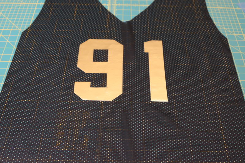 How To Press Adhesive Numbers Jersey - Athletic Mesh - Mood Fabrics - Fiona Athletic Set Free Sewing Pattern Tutorial - MDF537 - Mood Fabrics Sewciety Blog - Press the adhesive numbers to the jersey with muslin over the faux latex.
