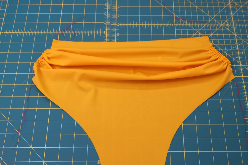 How To Pull Front Bottom Gathering Stitches - Gutermann Sew All Thread - Mood Fabrics - Amber Two Piece Cheeky Swimsuit Free Sewing Pattern Tutorial - MDF540 - Mood Fabrics Sewciety Blog - Pull on the top threads to gather the gathering stitches.